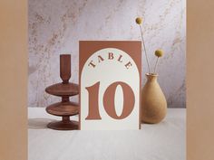 a table number sign next to two vases with flowers in them and a card that says table 10