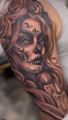 a woman's half sleeve tattoo with roses and a skull on her arm,