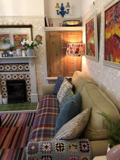 a living room filled with furniture and paintings on the wall above it's fireplace