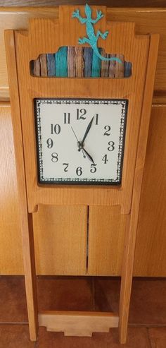 a wooden clock sitting on top of a table next to a wall mounted lizard figurine