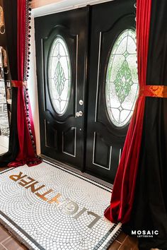 the front door is decorated with red drapes and black doors, along with two large round stained glass windows