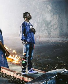 two young men standing next to each other in front of a fire