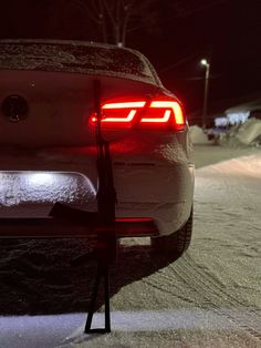 the tail light of a car on a snowy road at night with snow all over it