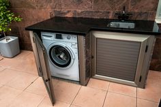 a washer and dryer sitting in a small room next to a sink with an open door