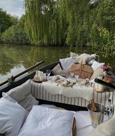 a boat filled with lots of pillows on top of a river next to a lush green forest