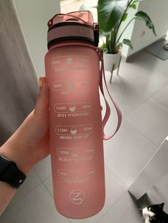 a person holding a pink water bottle in their hand