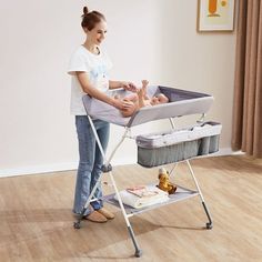 a woman standing next to a baby in a crib and changing it's diaper