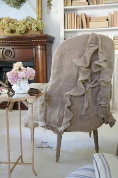 a living room with a chair covered in a ruffled blanket next to a fireplace