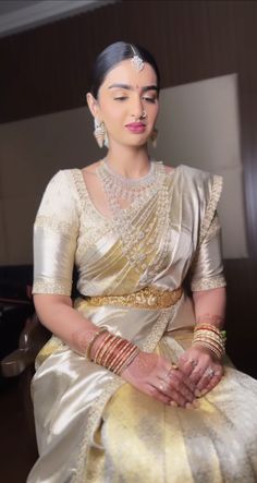 a woman sitting down in a white and gold dress