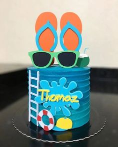 a birthday cake decorated with flip flops, sunglasses and a life preserver on top