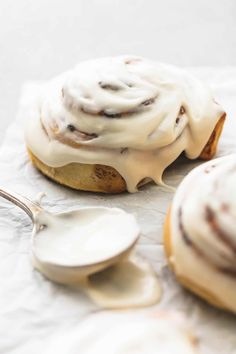 two cinnamon buns with icing on top and spoon