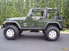 a green jeep is parked in front of some trees