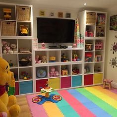 a child's playroom with toys and bookshelves on the wall, including a large teddy bear