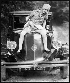 an old photo of a woman sitting on top of a car