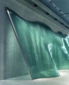 an artistic sculpture is shown in the middle of a concrete room with green water flowing down it