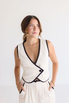 Get ready to stand out in style with The Elena Set! The sleeveless vest features V-neckline and a double-breasted design with a button closure for a sophisticated look. The adjustable back tie and cream and black contrasting edges make this vest a true statement piece. Pair it with the matching pants for a chic look. Details + Fit 100% Polyester Runs True to Size Hand Wash Cold Hang Dry V-Neckline Sleeveless Double Breasted Button Closure Adjustable Back Tie High Waist Button Closure Belt Loop S Cool Girl Style, Large Clothes, Short Vest, Cropped Vest, Vest White, Sleeveless Vest, Clothes Collection, Vest Top, Black Trim