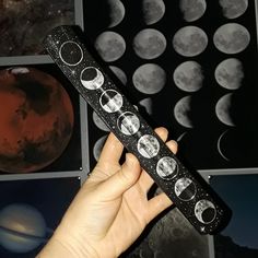 a hand holding a remote control in front of pictures of the moon and planets on display