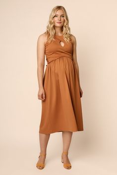 a woman wearing a brown dress and tan shoes stands in front of a beige background