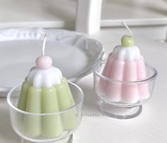 two small candles sitting on top of a table next to a glass bowl and plate