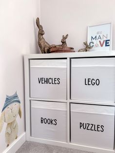 a toy rabbit sitting on top of a white shelf next to books and toys in bins