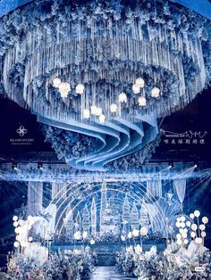 an elaborate chandelier hanging from the ceiling in front of a stage with flowers