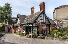 an old brick house with flowers growing on the front and side of it's roof