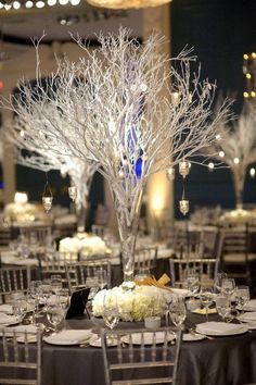 the centerpieces are decorated with white flowers and branches