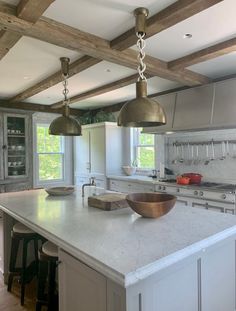 a large kitchen with an island and two pendant lights hanging from it's ceiling