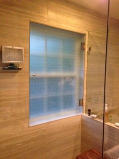 a bathroom with a glass shower door and toilet in the corner, next to a sink