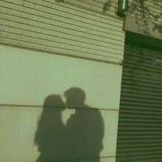 a shadow of two people standing next to each other on the side of a building