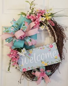 a welcome sign is hanging on the front door with pink flowers and green ribbon around it