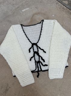 a knitted sweater with black and white details on the front, sitting on concrete