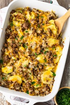 a casserole dish with meat, potatoes and cheese in it on a wooden table