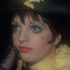 a close up of a person wearing a hat with fake eyelashes and makeup on her face