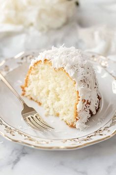 a piece of coconut cake on a plate with a fork and napkin next to it