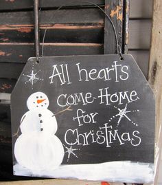 a sign that says all hearts come home for christmas with a snowman on it