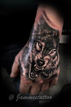 a man's hand with a wolf tattoo on it