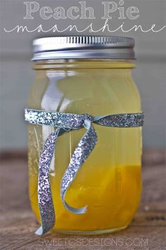 a mason jar filled with yellow liquid and silver glitter ribbon