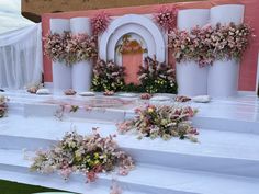 an outdoor wedding setup with flowers on the stage and columns in front of it,