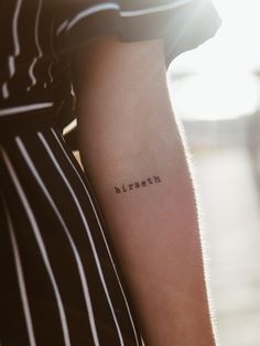 a woman's arm with the word kirsch tattooed on it in black ink