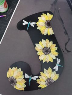 the letter j is decorated with sunflowers and dragonflies on black paper,