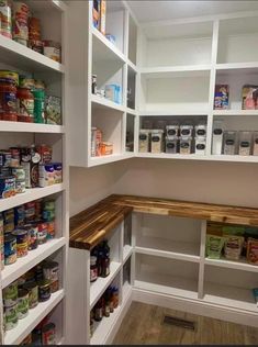 an organized pantry with white shelving and wooden shelves