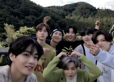 a group of young people standing next to each other in front of a mountain range