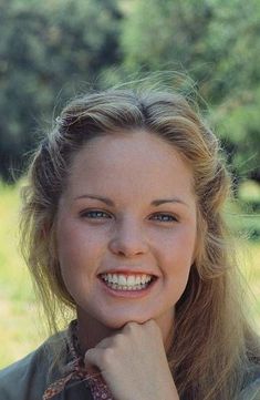 a woman smiling with her hand on her chin