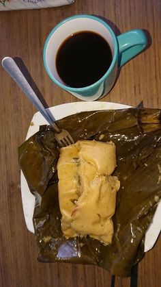 a plate with some food on it next to a cup of coffee and spoons