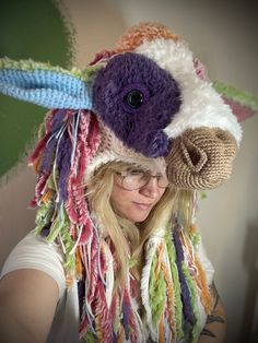 a woman wearing a knitted cow hat with multicolored yarns on it