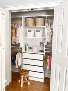 an open closet with clothes and baskets on the shelves, next to a step stool