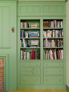 a green bookcase with many books in it next to a fire place and fireplace