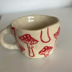 a red and white cup with mushrooms on it