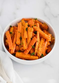 a white bowl filled with carrots on top of a marble counter next to a napkin